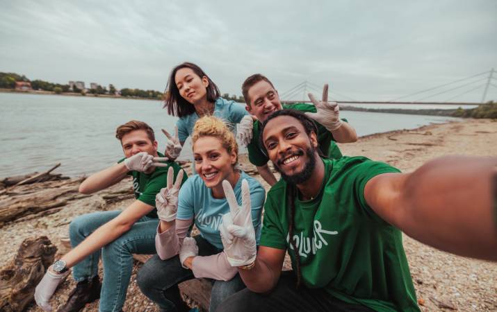 A diverse group of happy volunteers posing for a selfie on a beach