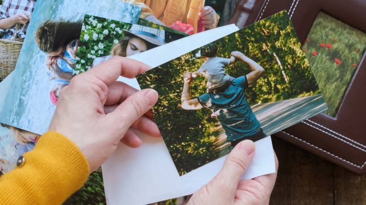 Hands sorting through family photographs on a table.