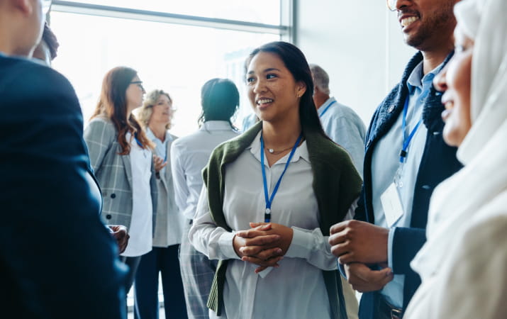 A diverse group of young professionals chatting at a networking event with a young women smiling in the centre