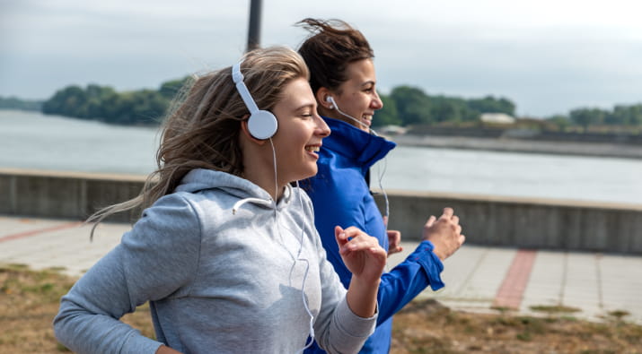 Two woman jogging alongside a river